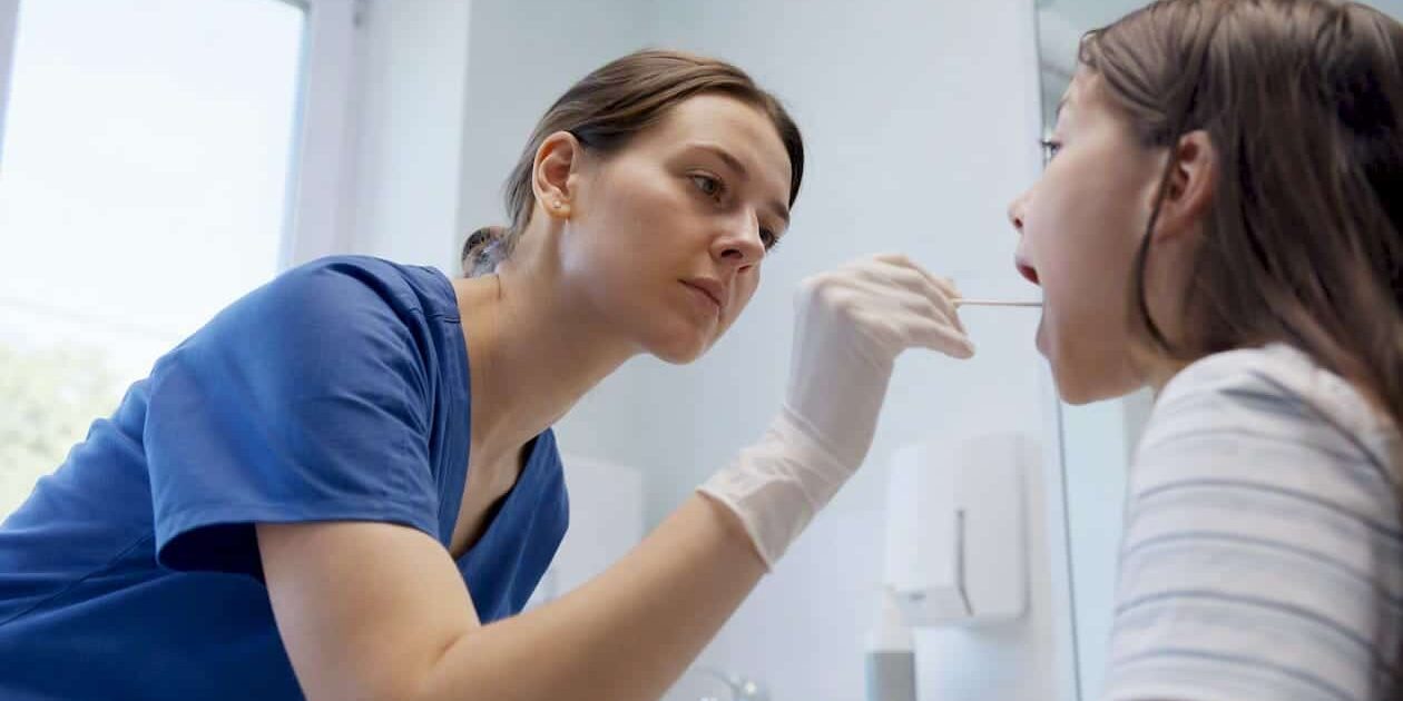 1786241878006_Clinician-performing-throat-swab-for-strep-test Clinician performing throat swab for strep test