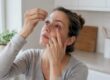 Hand applying eye drops to a red eye