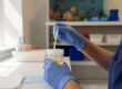 Gloved hands holding urinalysis dipstick near urine sample