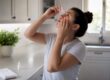 Hands applying eye drops in bathroom