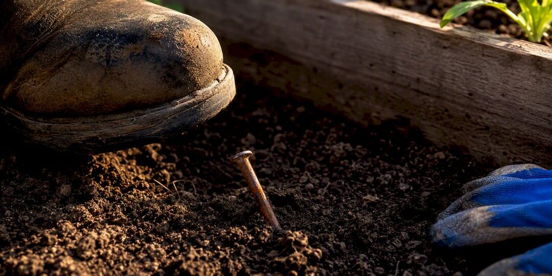 1788444491693_Rusty-nail-partly-hidden-in-garden-soil Rusty nail partly hidden in garden soil