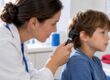 Clinician examining child’s ear with otoscope