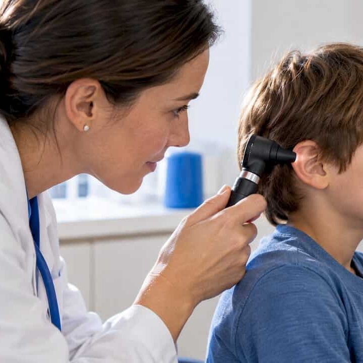 Clinician examining child’s ear with otoscope