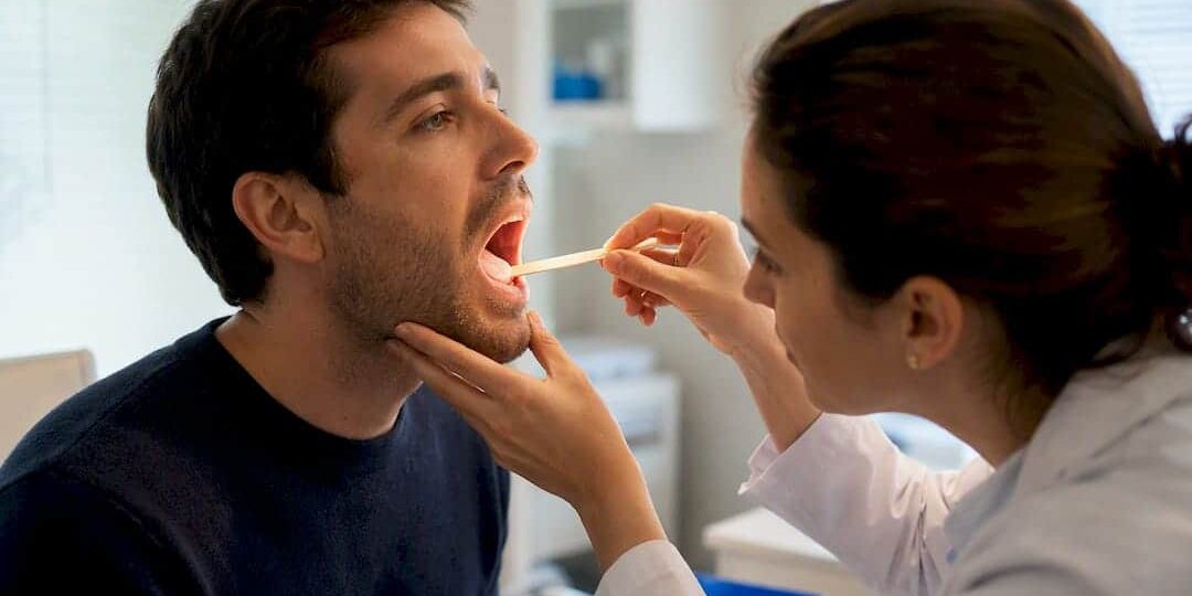 1790257080098_Clinician-examining-patient-with-sore-throat Clinician examining patient with sore throat