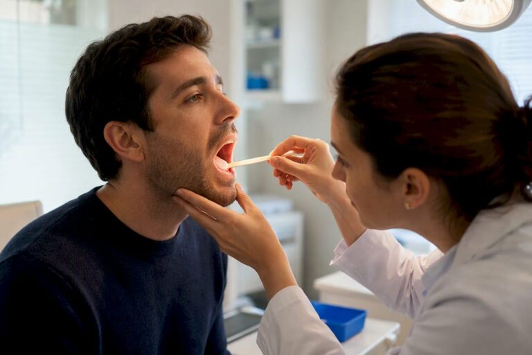 Clinician examining patient with sore throat