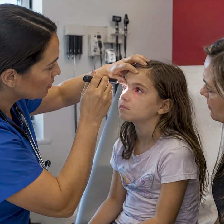 Clinician assessing child's red eye with parent